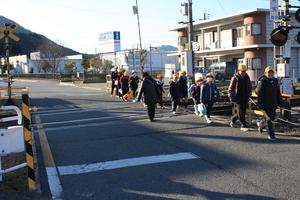 踏み切りを黄色い帽子を被った子供達が一列に並んで歩いている写真